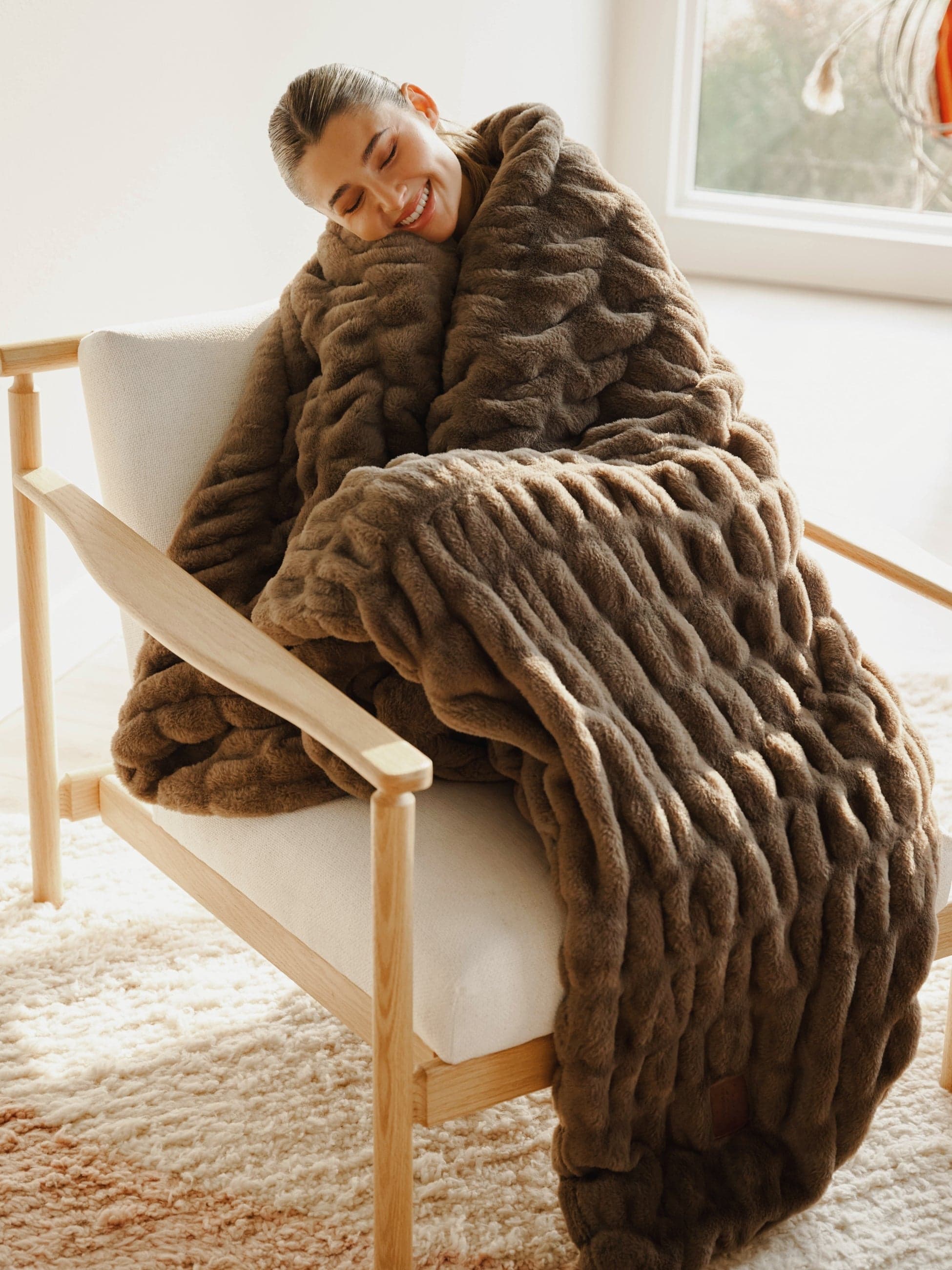 A generous brown blanket wrapped around a person relaxing on a sofa